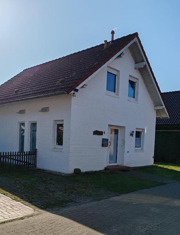 a white house with a brown roof at Haus Amsel am Heeder See in Heede