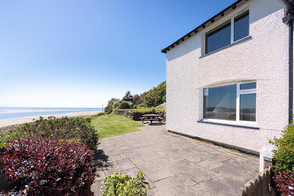 a building with a patio next to the beach at 3 Bed in Aberdyfi oc-dy024 in Aberdyfi
