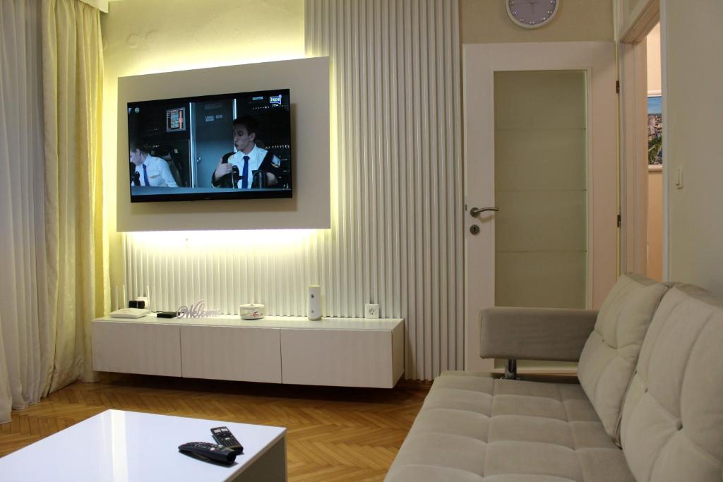 a living room with a couch and a tv on a wall at Amigo Apartment in Mostar
