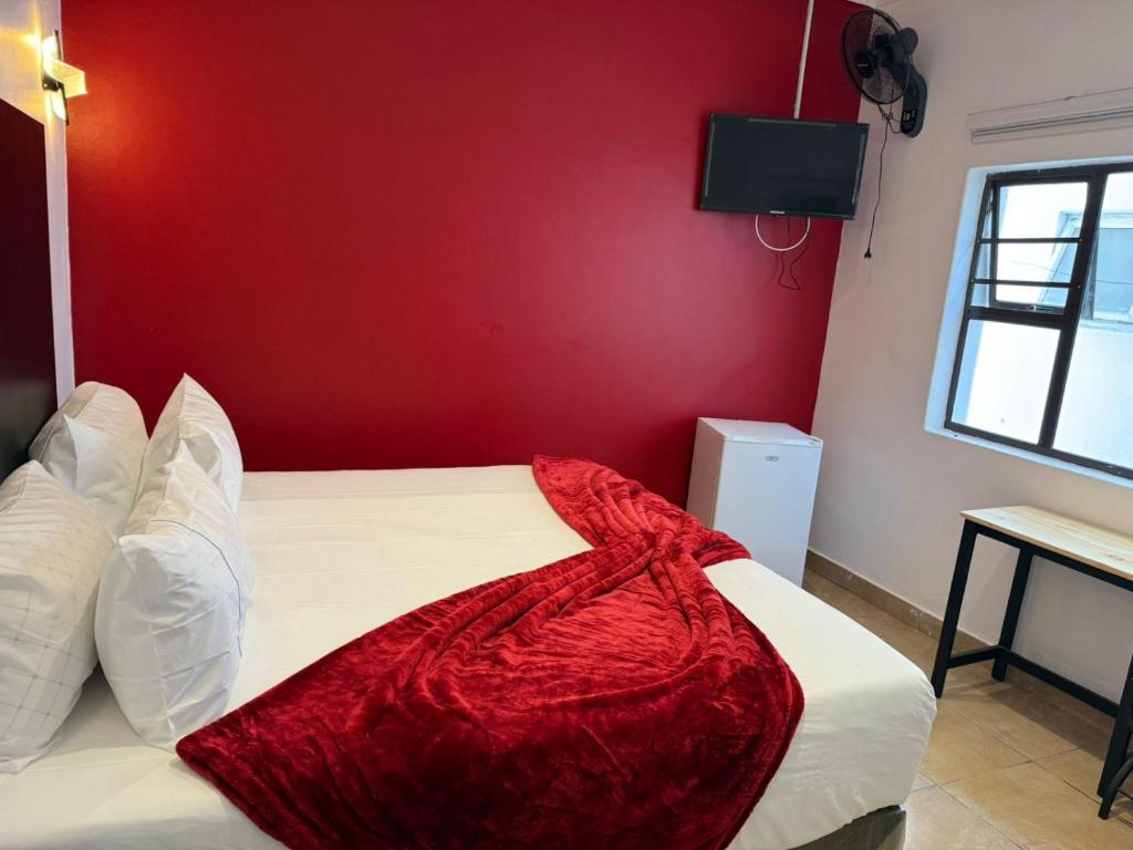 a bedroom with a bed with a red wall at Black & White Guest House in Parow