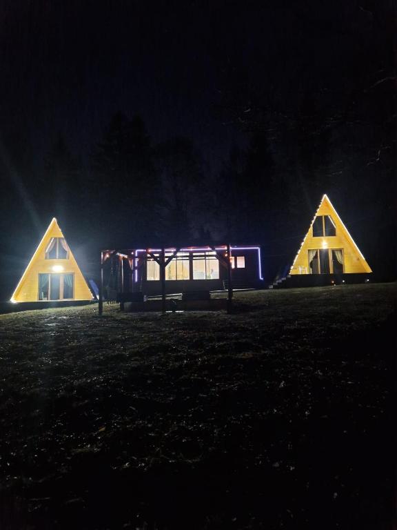 a couple of houses lit up at night at Casutele Anei- Aframe&Spa in Rişca