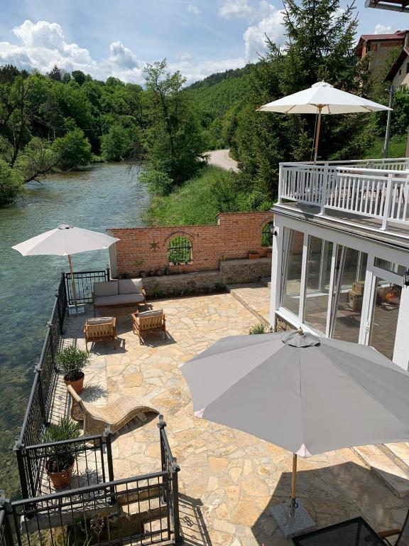 a patio with tables and umbrellas next to a river at Sokograd Entire House in Šipovo