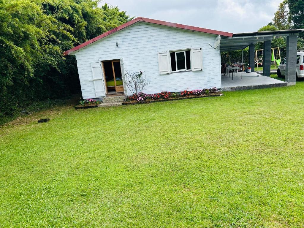 a small white house with a grass yard at Ti' case la plaine in La Plaine des Palmistes