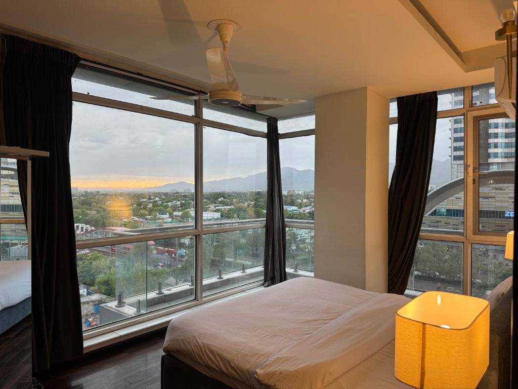 a bedroom with a bed and a large window at Elysium Tower Luxury Apartments Islamabad Opposite Centaurus Mall in Islamabad
