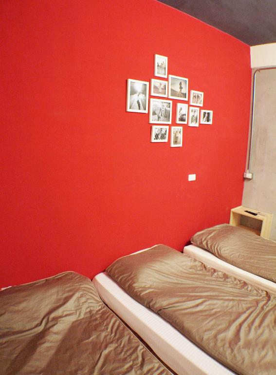 two beds in a room with a red wall at Knock Knock Hostel in Kaohsiung