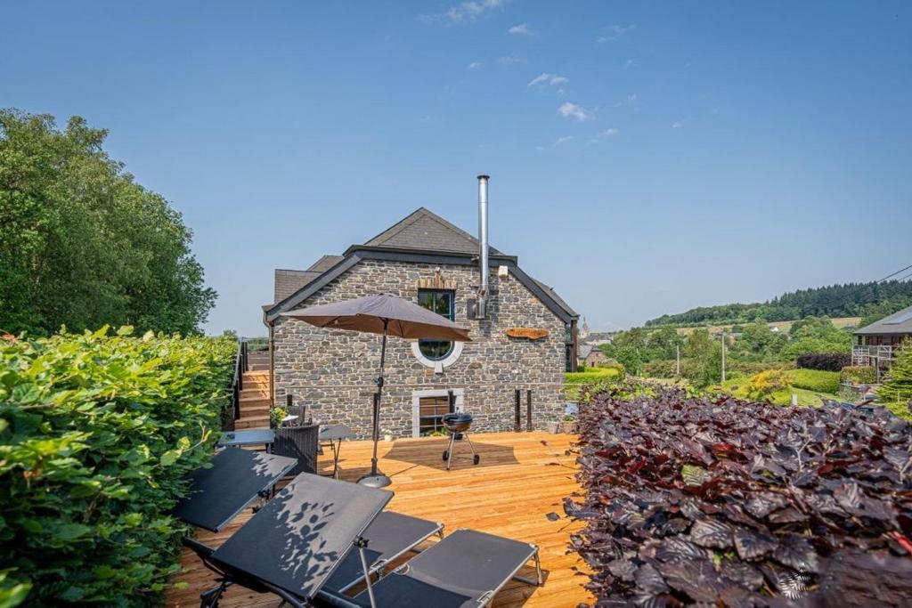 a house with chairs and an umbrella on a wooden deck at Gîte Libre’Air in Redu