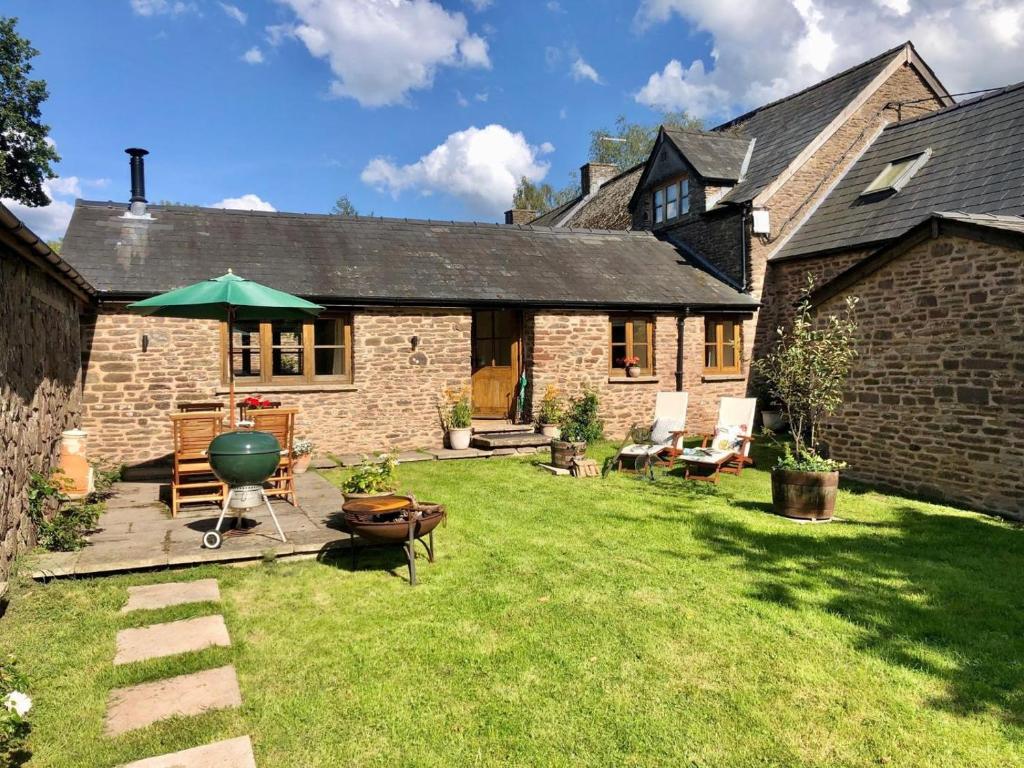 a backyard of a brick house with a green umbrella at 1 Bed in Chepstow oc-91941 in Chepstow