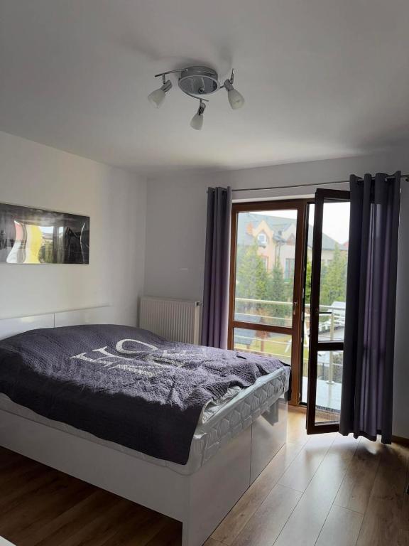 a bedroom with a bed and a large window at TOBI-pokoje gościnne in Łeba
