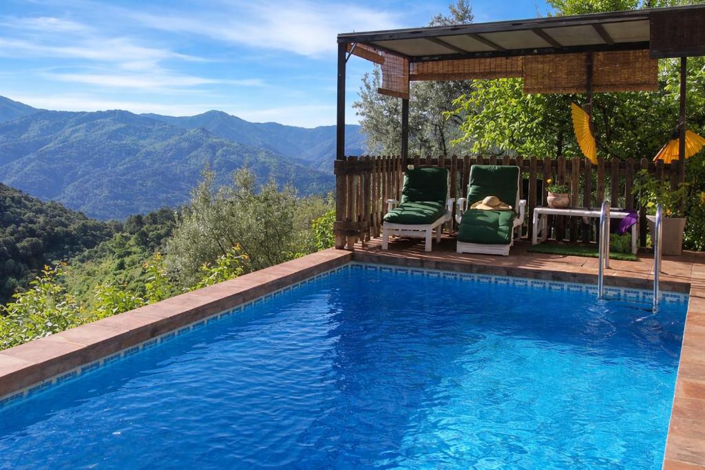 a swimming pool with two chairs and a gazebo at Complejo El Alambique in Algatocín