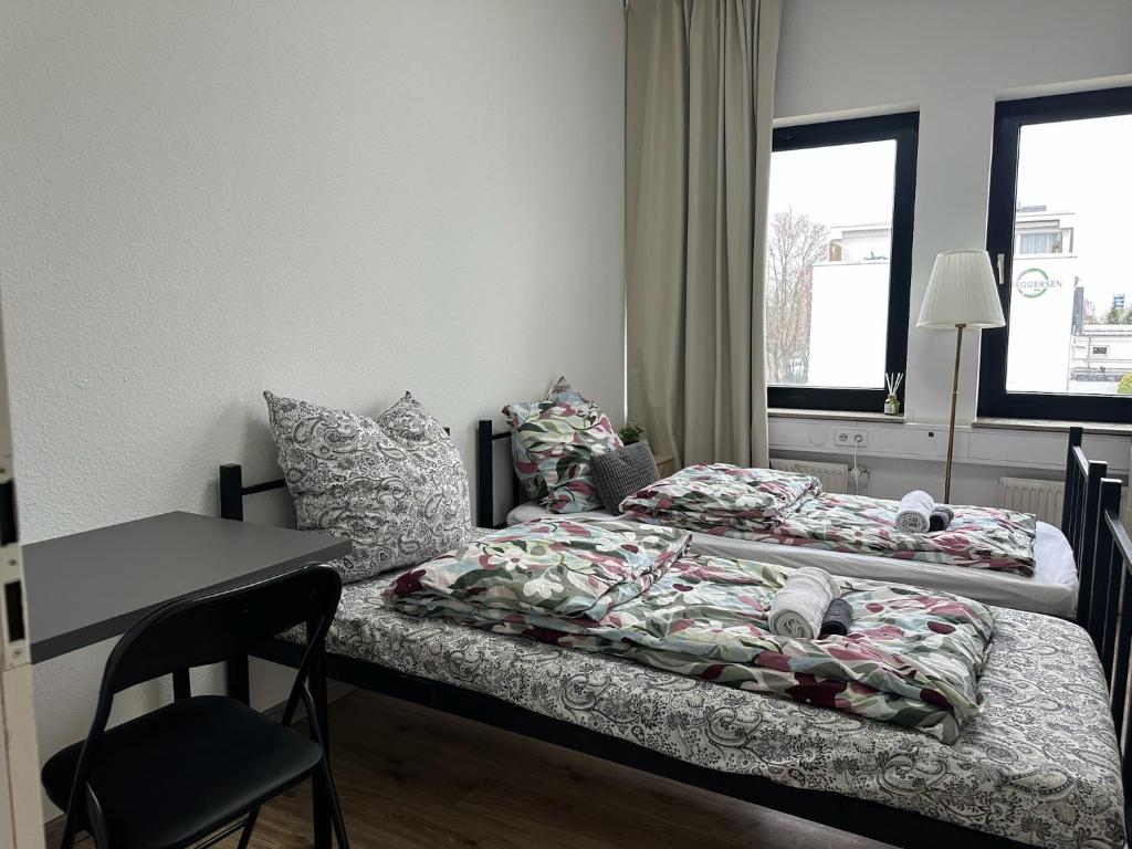 two beds in a room with a table and a desk at Boberger Hostel in Hamburg