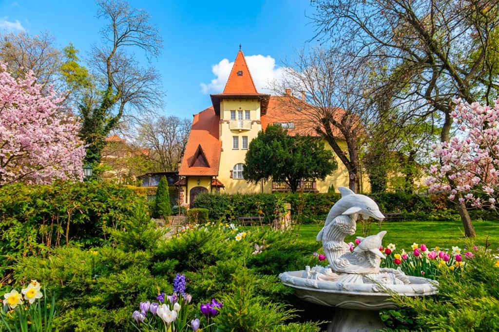 a garden with a statue in front of a house at Fried Kastély Hotel Simontornya in Simontornya