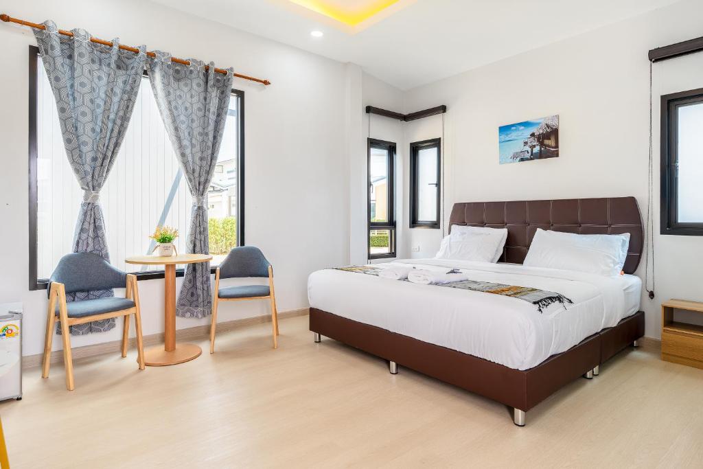 a bedroom with a bed and a table and chairs at Deluxe Hotel Chaiyaphum in Chaiyaphum