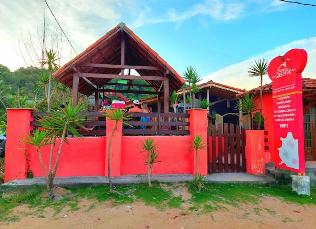 a house with a red fence and a red wall at Pousada Casarão Piúma in Piúma