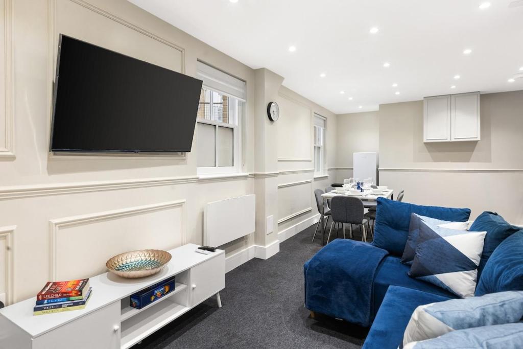 a living room with a blue couch and a flat screen tv at Spacious 2-Bed Home in Chipping Barnet in Barnet