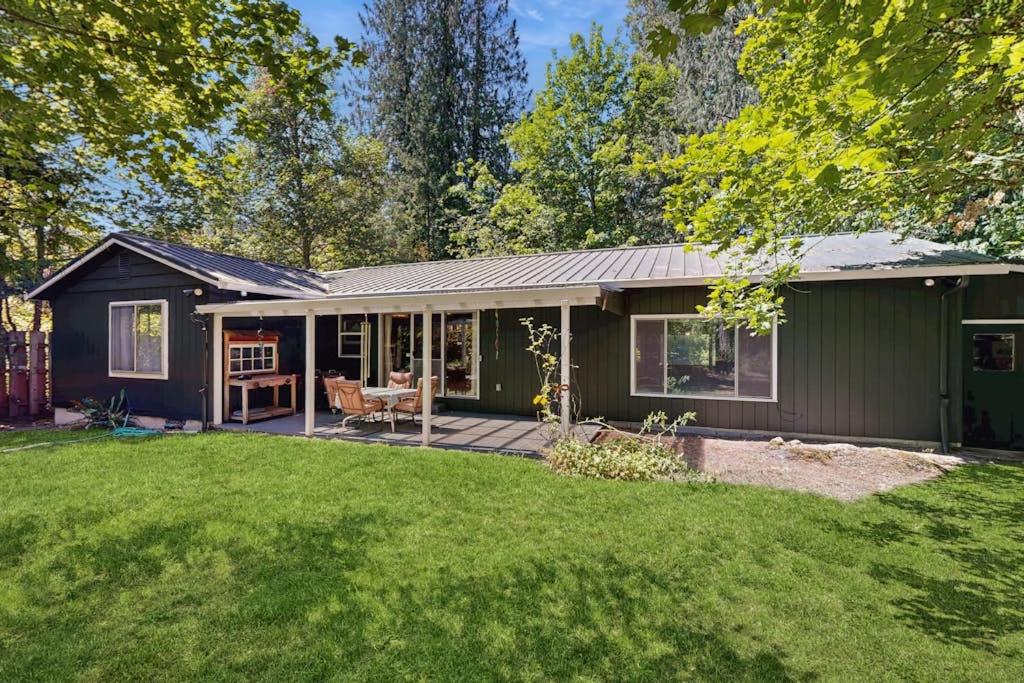 a green house with a deck and a yard at Spacious home with full kitchen wifi private backyard & grill in Welches