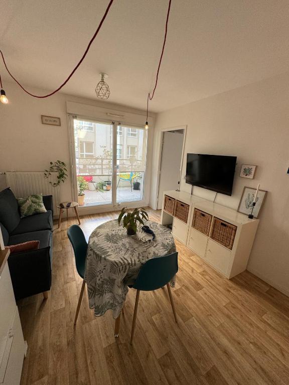 a living room with a table and a tv at Appartement T2 à Chelles - Paris, CDG & Disneyland à proximité, parking privé in Chelles