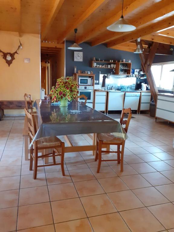 a dining room with a table and chairs and a kitchen at La grange des chouettes in Ilheu