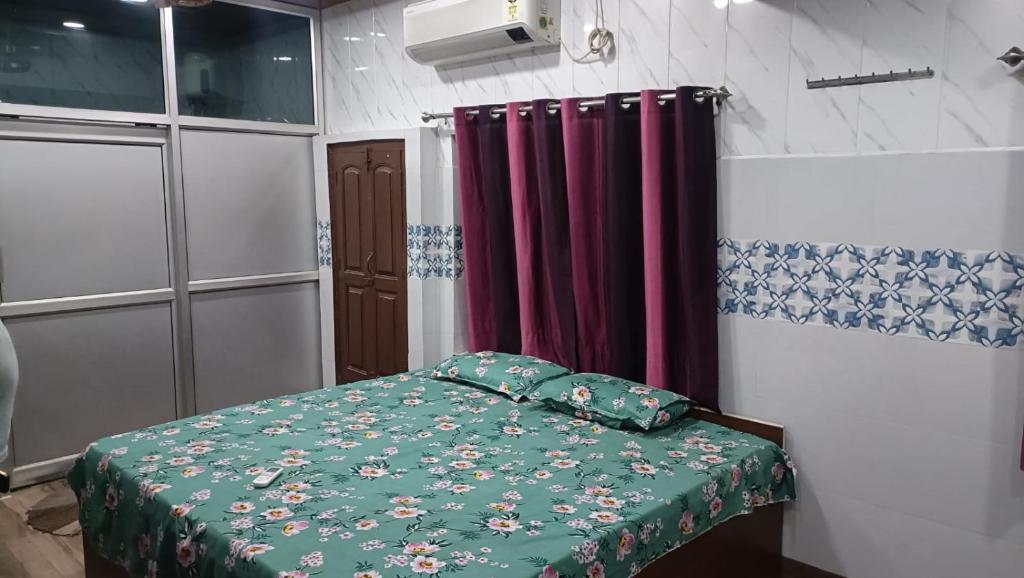 a small bedroom with a bed with a green comforter at Sakchi Gopal Ashram in Vrindāvan