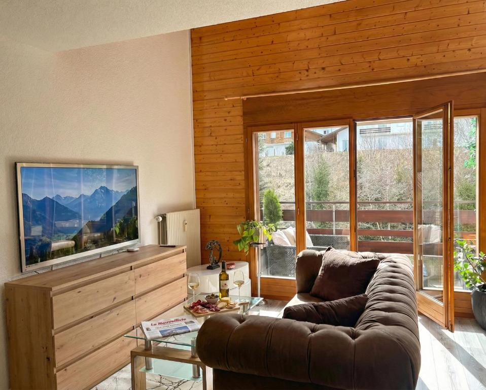a living room with a couch and a flat screen tv at Duplex lumineux avec vue in Vionnaz