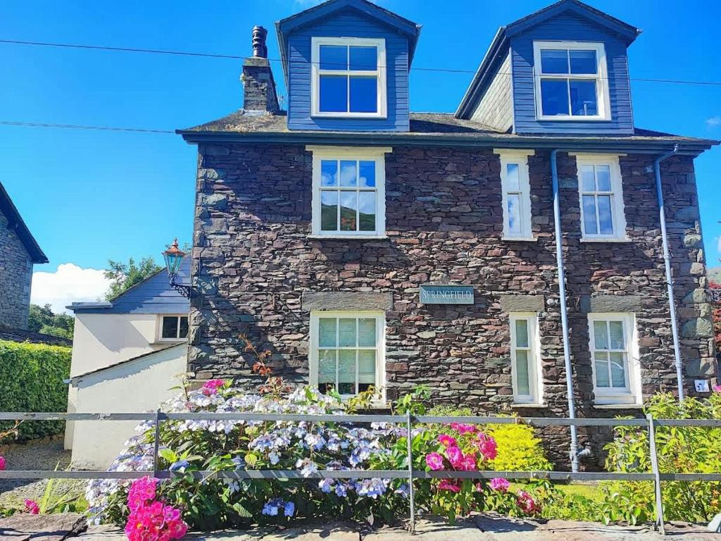 a stone house with flowers in front of it at Springfield House in Grasmere