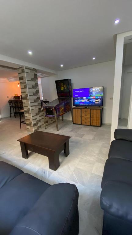 a living room with a couch and a table and a tv at SunWave Chott Meriem in Sousse