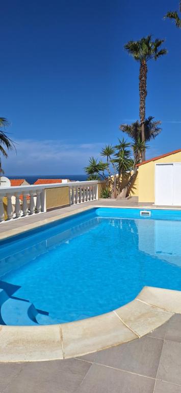 a blue swimming pool with palm trees in the background at Casa Panorama in La Pared