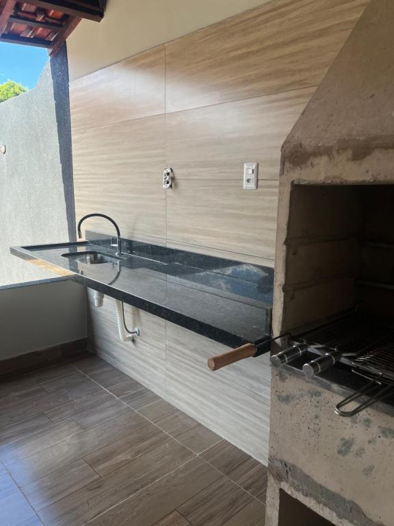 a kitchen with a counter with a sink and an oven at Casa com área de lazer tranquila e espaçosa! in Campo Grande