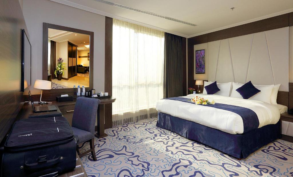 a hotel room with a bed and a desk at Swiss Flora Royal Hotel Riyadh in Riyadh