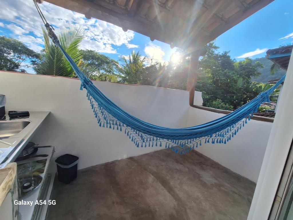 a hammock on a balcony with the sun in the background at Alma Surf House in Boicucanga