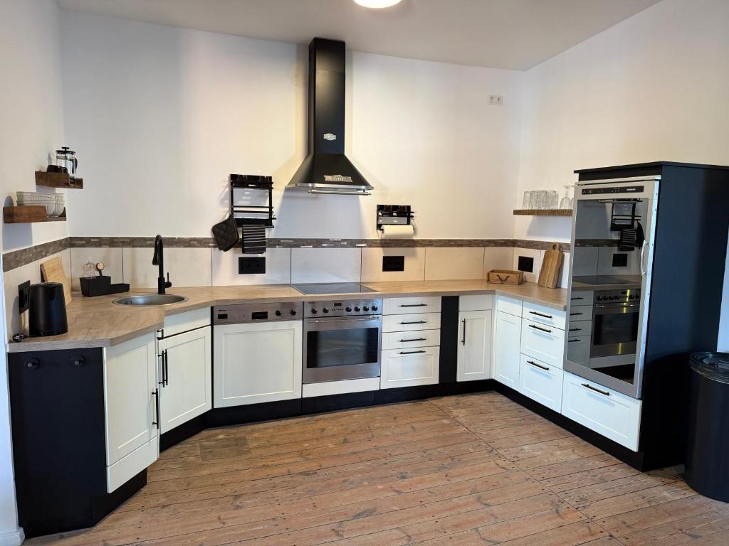 a large kitchen with white cabinets and appliances at Speicherstübchen im alten Speicher in Schönberg