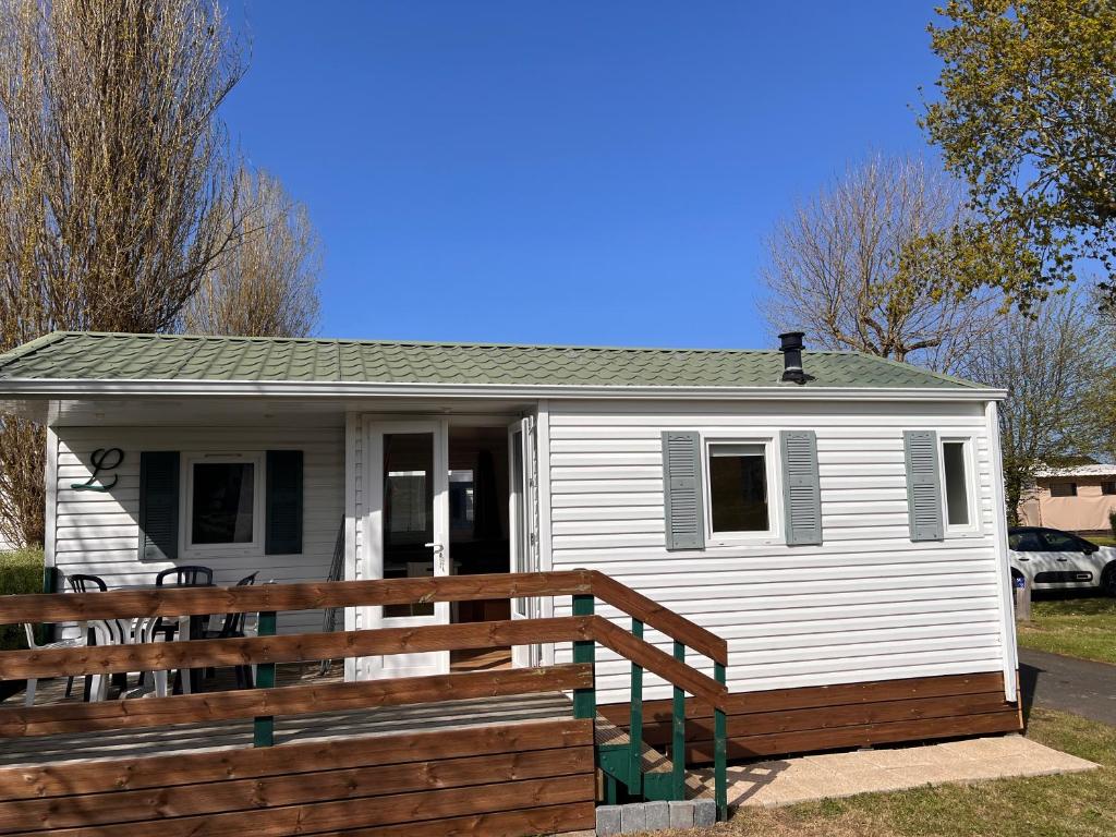 a small white house with a wooden porch at Mobile Home à Louannec in Louannec