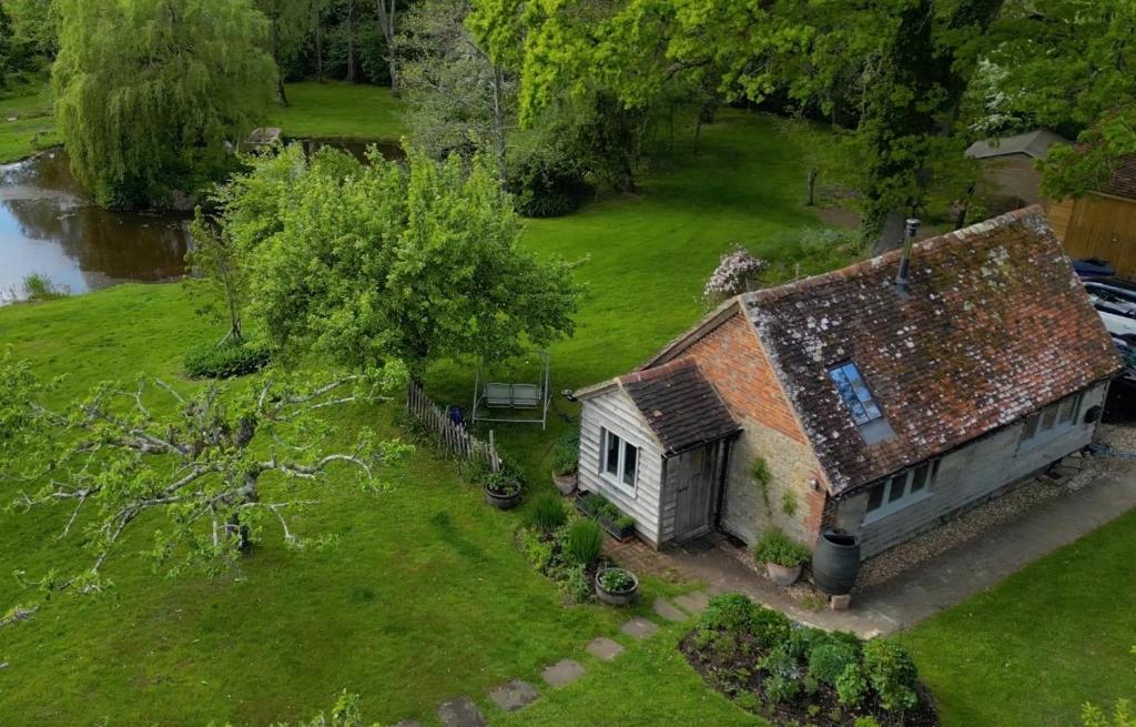 an old house in a field next to a river at Secluded 17th Century converted barn in Midhurst