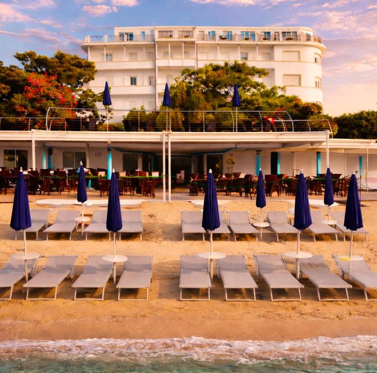 a group of chairs and blue umbrellas on a beach at LVG Hotel Collection - Grand Hotel Mediterranee in Alassio