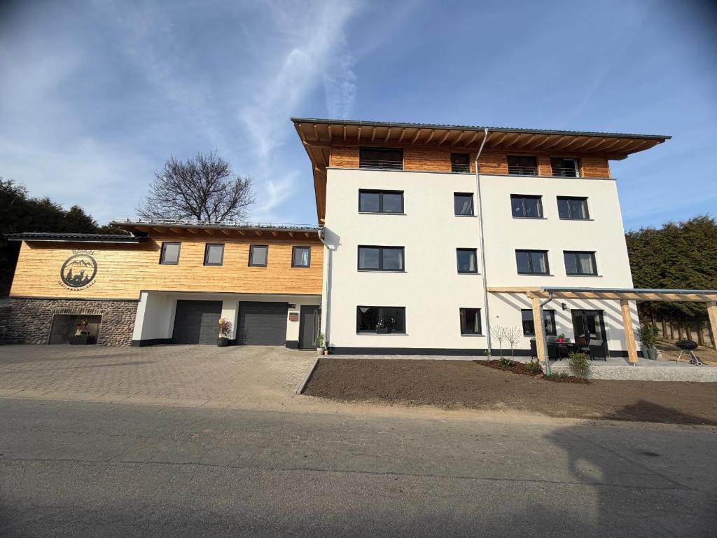 a large white building with a wooden roof at Ferienwohnungen Rauch in Regen
