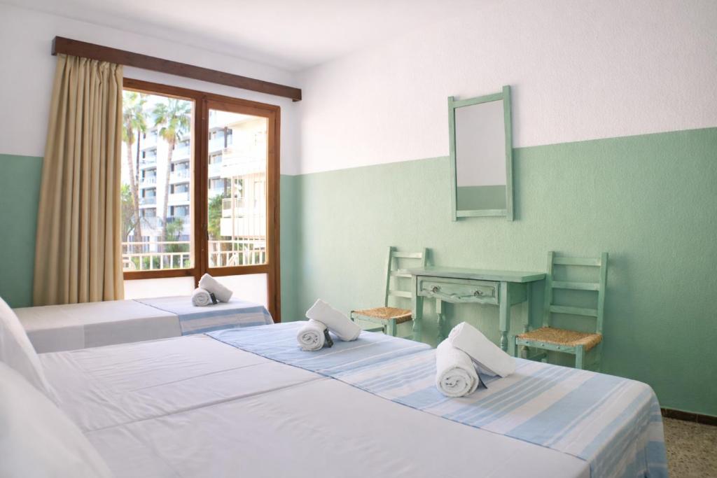 two beds in a room with a desk and a mirror at Hostal Santa Ana in Lloret de Mar