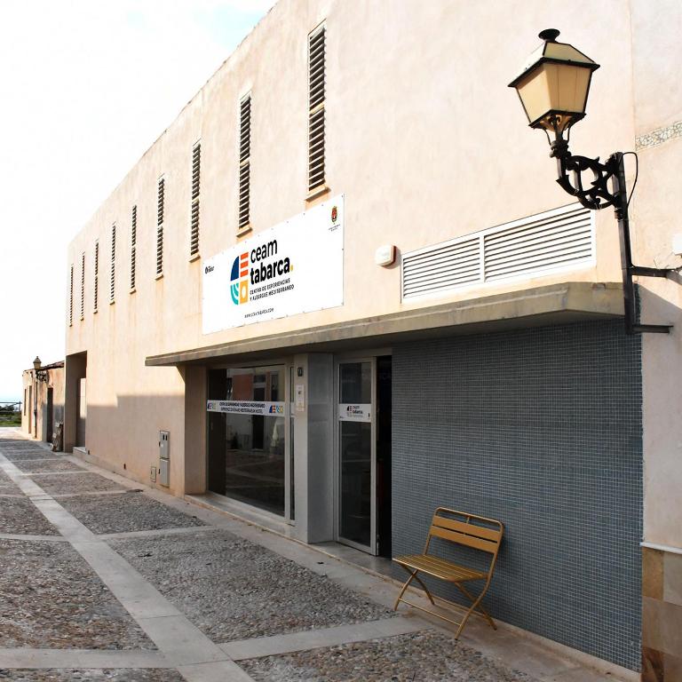 a chair sitting outside of a building with a street light at CEAM Tabarca in Tabarca