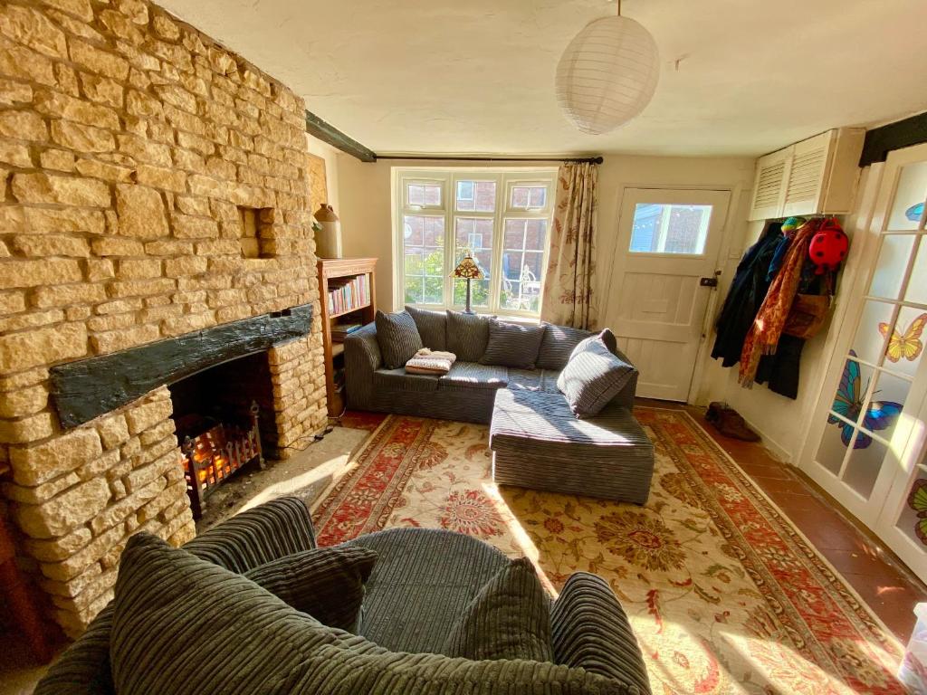 a living room with a couch and a stone fireplace at Butterfly Cottage in Knowle