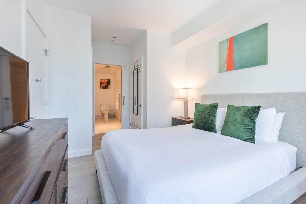 a bedroom with a white bed and a television at Seaport Retreat - Rooftop Pool & Gym in Boston