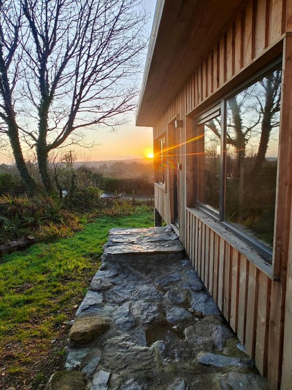 a house with a stone walkway next to a window at The Perch - Romantic Cabin with Sunset Views in Gurteenulla