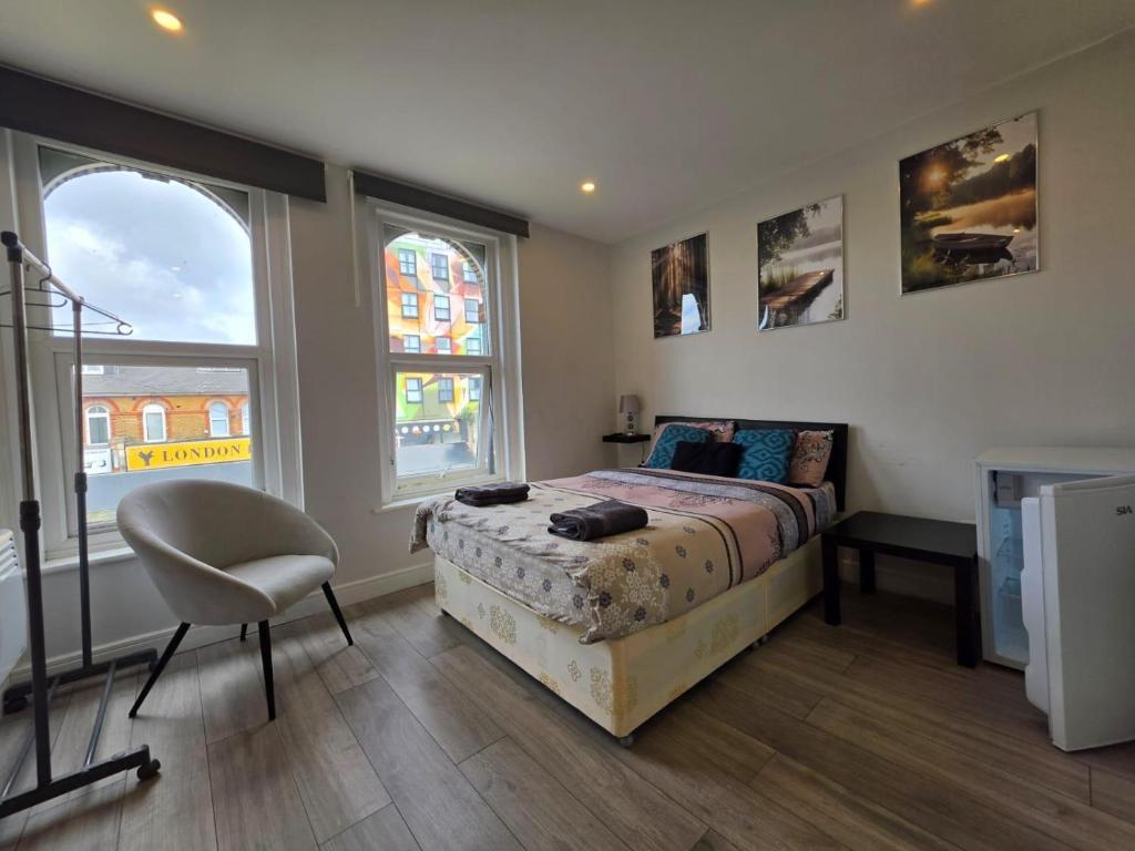 a bedroom with a bed and a chair and two windows at The Brigstock Nest in Thornton Heath