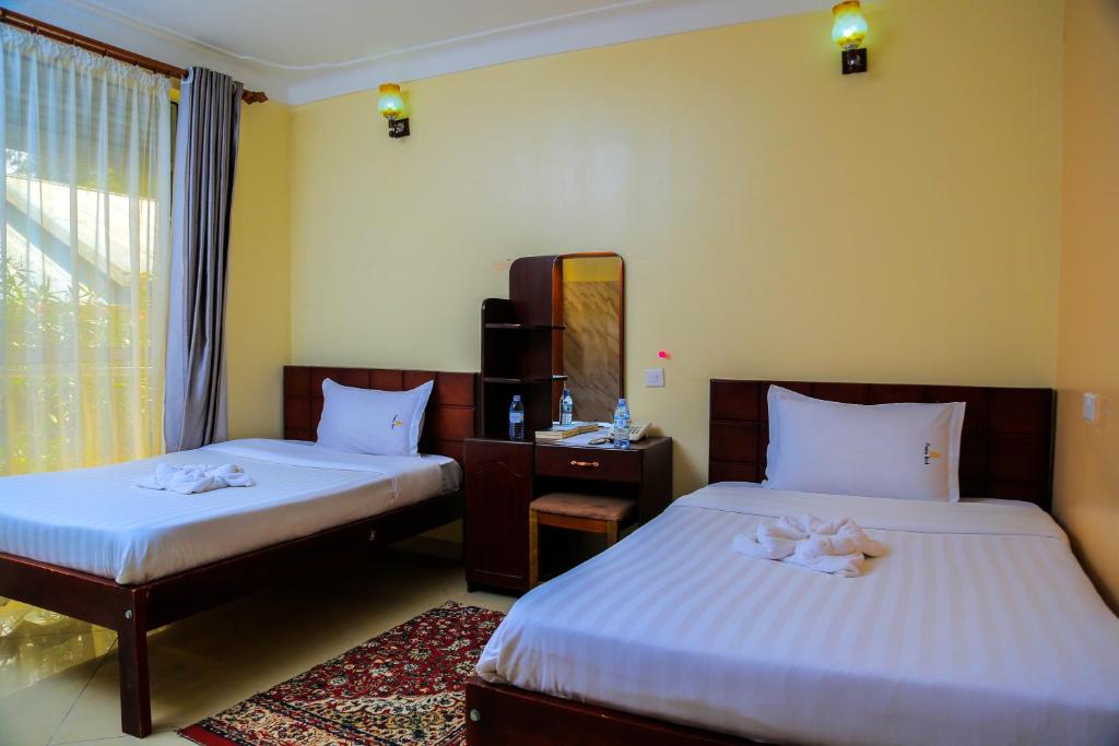 a hotel room with two beds and a mirror at Premier motel in Bushenyi