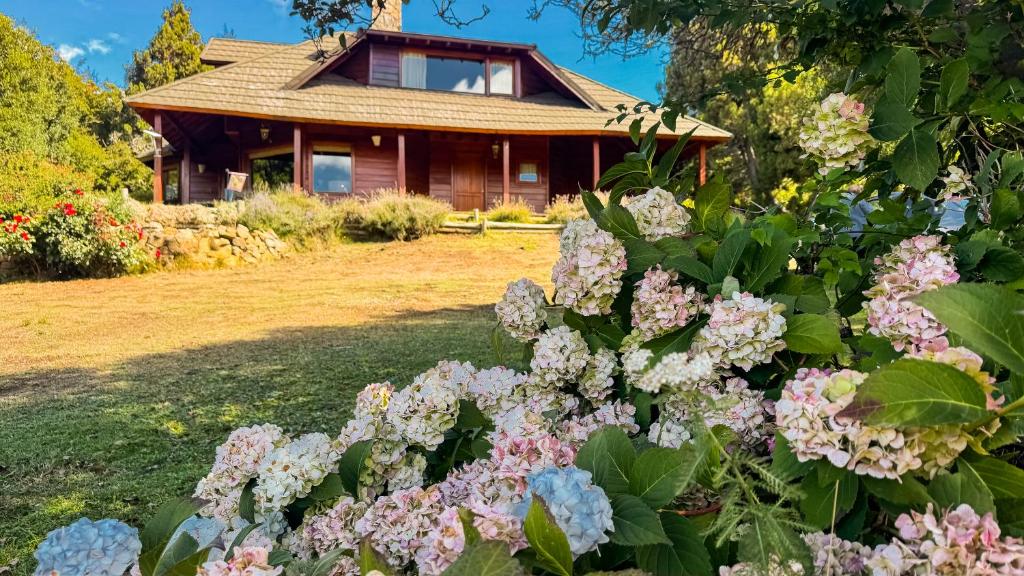 a house with flowers in front of it at Viejo Radal "Casa de Montaña" in San Martín de los Andes