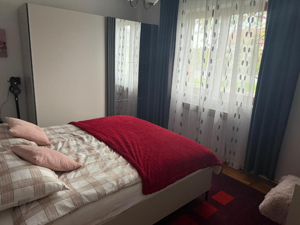 a bedroom with a bed with a red blanket on it at Laganini Cozy Home in Velika Mlaka