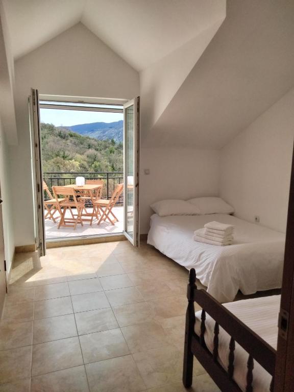 a bedroom with a bed and a balcony with a table at Hillside Apartments in Sutorina