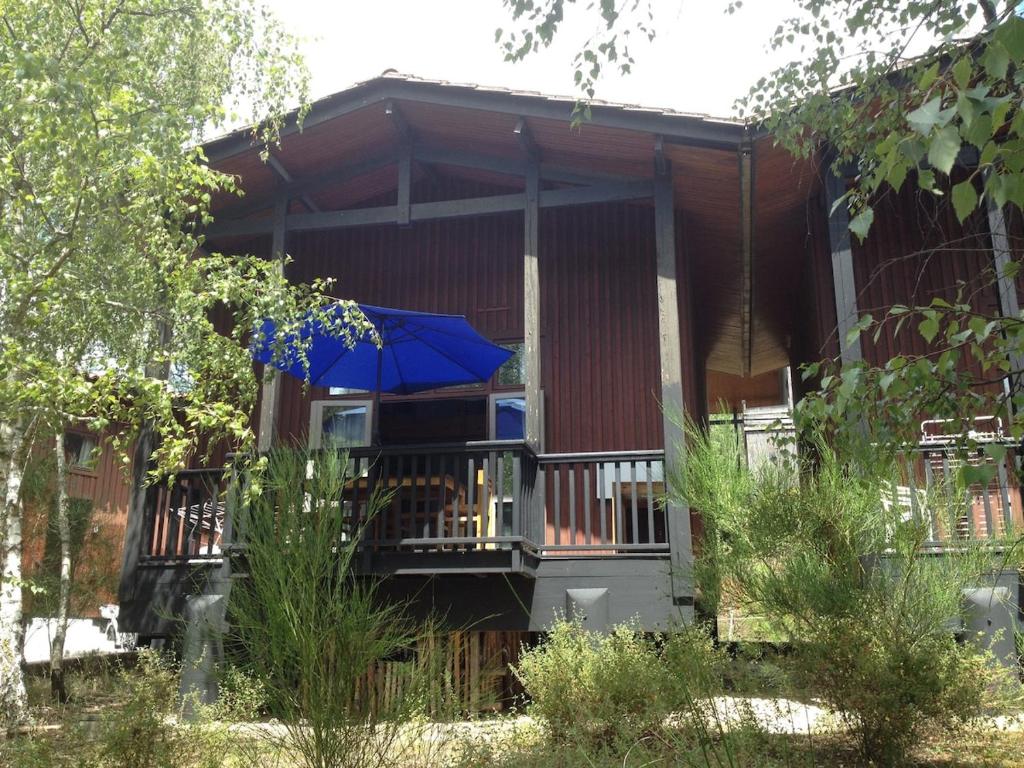 a house with a porch with a blue umbrella at chalet dans les pins in Carcans