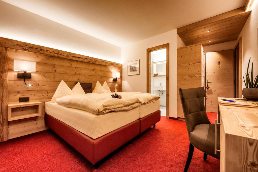 a bedroom with a large bed and a chair at AlpinArosa in Arosa