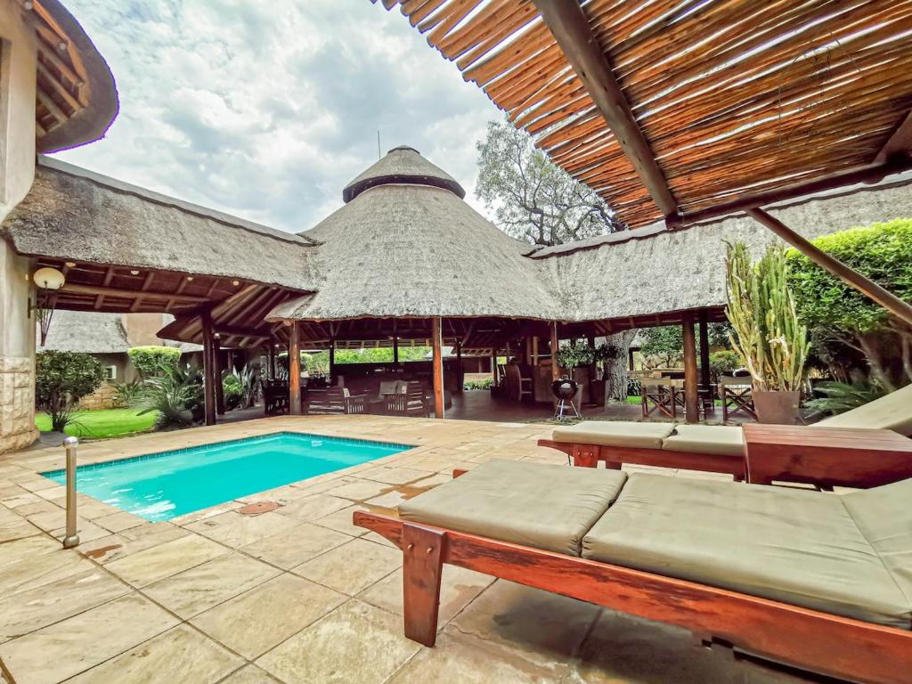 an outdoor patio with a pool and a thatch roof at Cherry Creek at Zebula in Warmbaths