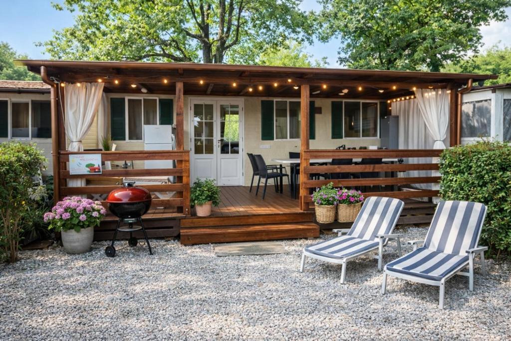 a house with a deck with two chairs and a grill at Bungalow Resort Ameglia in Ameglia