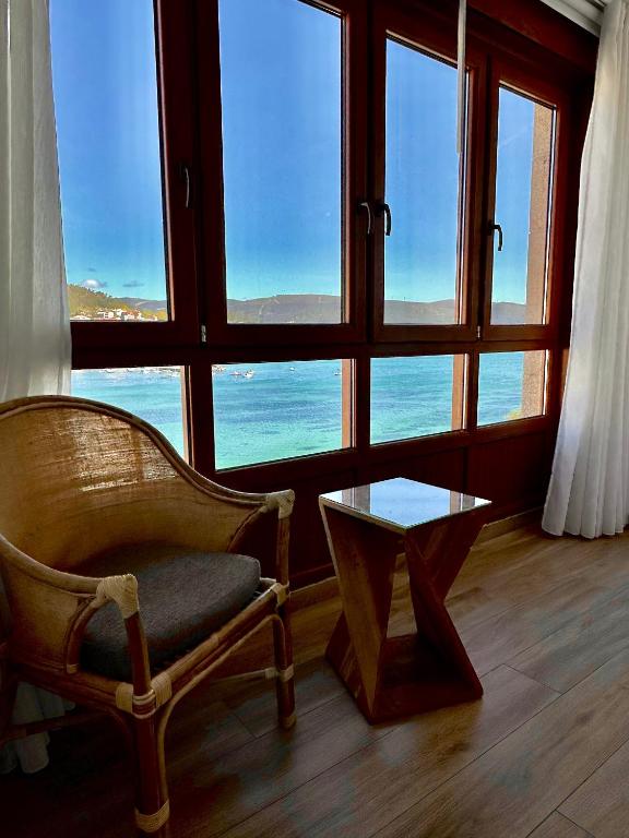 a room with a chair and a table and windows at GH Beiramar in Cee