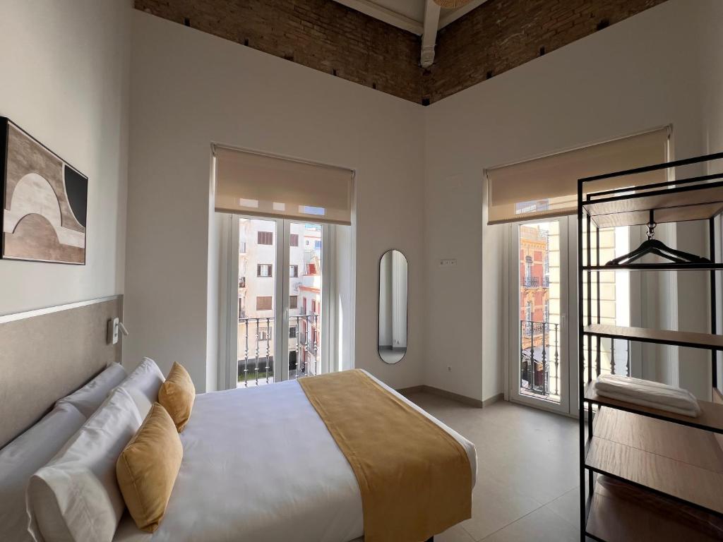 a bedroom with a bed and some windows at Iberflat San Gregorio in Seville